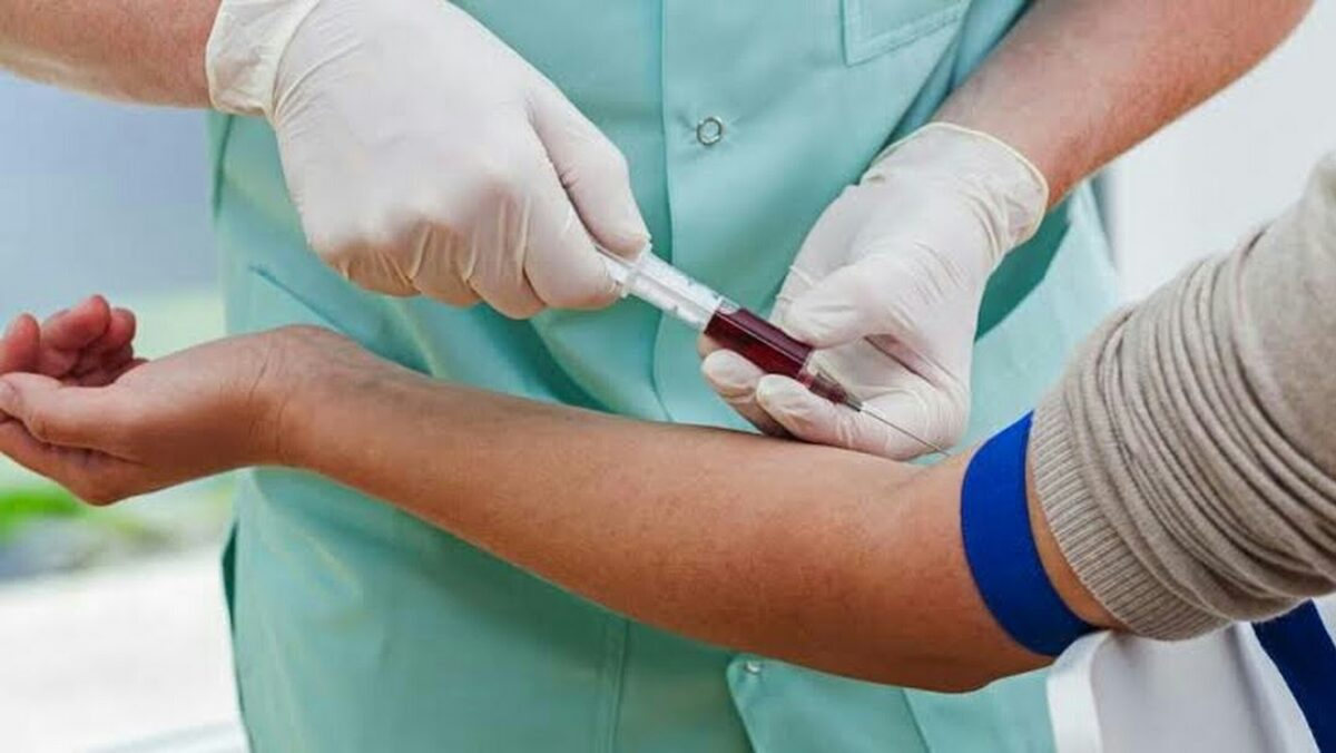 Professional nurse collecting blood sample at home from elderly patient